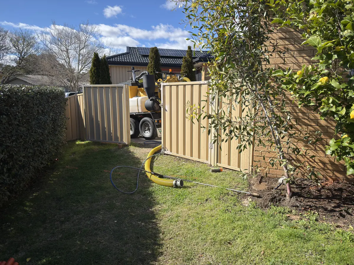 Vacuum hose routed through a narrow side passage beside a house