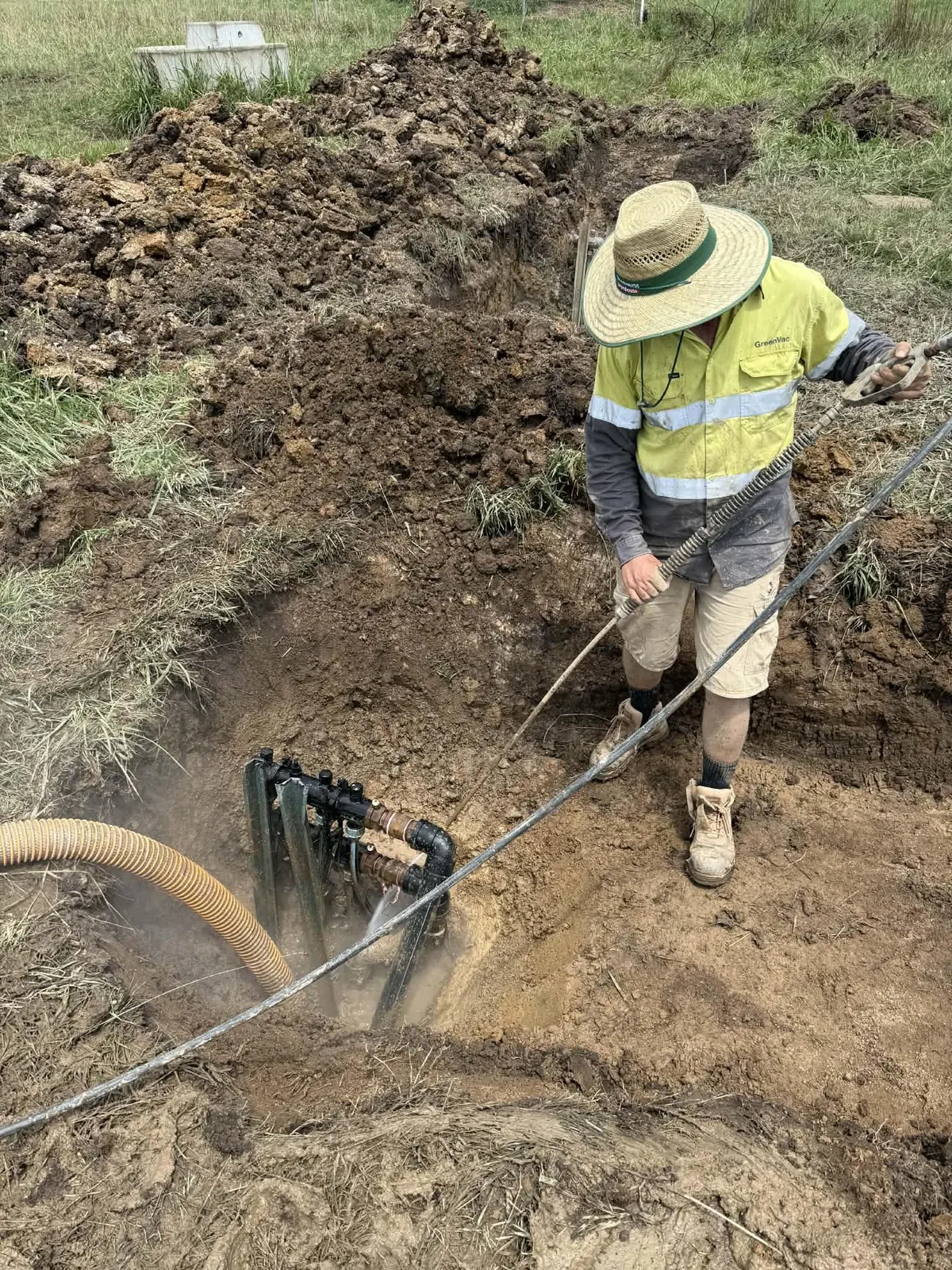 James operating GreenVac's water lance and vacuum hose beside exposed underground pipework