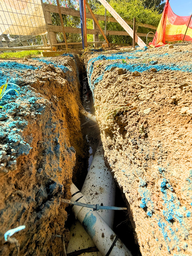 Exposed underground pipework within a narrow service trench