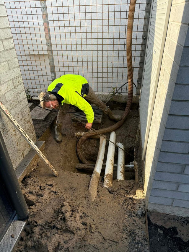 GreenVac operator using hydrovac equipment in a confined space between buildings