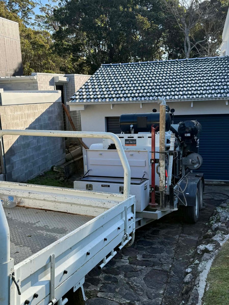GreenVac compact hydrovac rig operating in tight access between garage doors